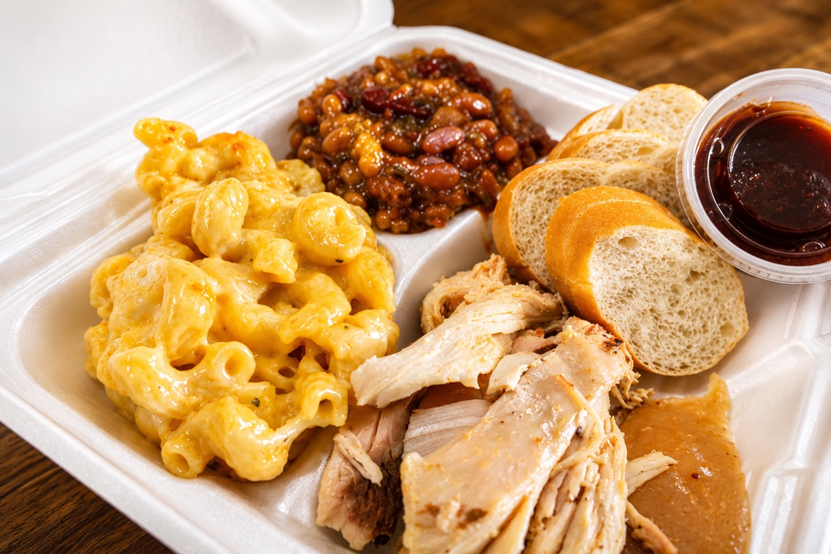 Smoked chicken plate with mac and cheese, baked beans, bread, and sauce